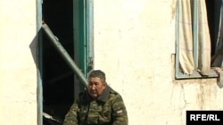 A Kazakh officer sits in front of a house destroyed in recent flooding.