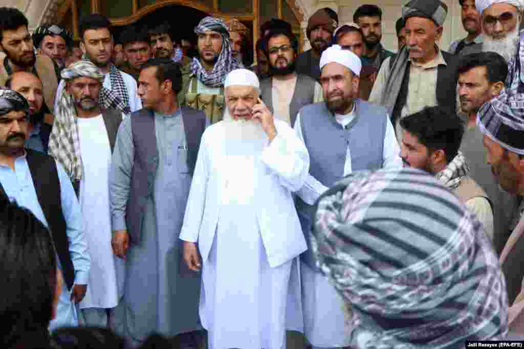 Ismail Khan (on telephone), a veteran of the Soviet-Afghan war of the 1980s, with supporters as he prepares to defend the area against the Taliban advance on July 9. Khan survived an assassination attempt by the Taliban in 2009.&nbsp;