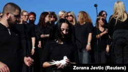 Një grua mban një pëllumb të bardhë ndërsa njerëzit mblidhen për të shënuar përvjetorin e parë të shembjes fatale të çatisë në stacionin e trenit në Novi Sad në nëntor 2024, ku humbën jetën 16 persona njerëz, Novi Sad 1 nëntor 2025. 