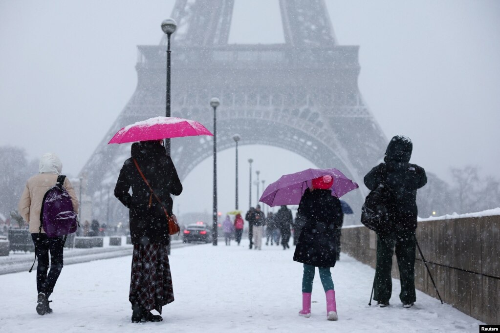 Njerëz ecin nën reshjet e borës pranë Kullës Eiffel në Paris, ndërsa moti dimëror me borë dhe temperatura të ulëta ka përfshirë një pjesë të madhe të vendit, Francë, më 5 janar 2026.