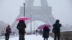 Ljudi prolaze pored Ajfelovog tornja dok snježne pahulje prekrivaju Pariz, u jeku hladnog talasa koji je pogodio Francusku.