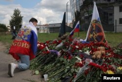 مردی با پرچم روسیه مقابل یادبود موقت در سن پترزبورگ، پس از مرگ پریگوژین