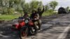 Ukrainian servicemen ride a motorcycle on a road outside a village recently retaken by Ukrainian forces near Kharkiv on May 13. 