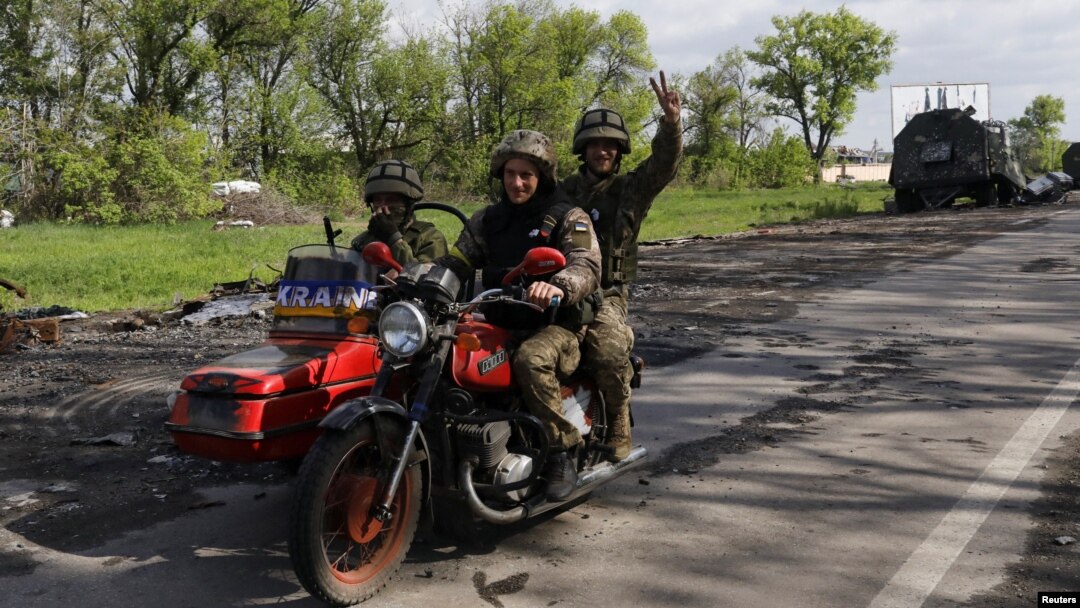 Ukrainian servicemen ride a motorcycle on a road outside a village recently retaken by Ukrainian forces near Kharkiv on May 13. 