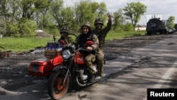 Ukrainian servicemen ride a motorcycle on a road outside a village recently retaken by Ukrainian forces near Kharkiv on May 13. 
