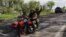 Ukrainian servicemen ride a motorcycle on a road outside a village recently retaken by Ukrainian forces near Kharkiv on May 13. 