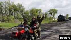 Ukrajinski vojnici voze se motociklom cestom koja povezuje Harkiv i selo koje je nedavno ponovno zauzela ukrajinska vojska, 13. maja 2022.