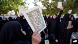 Disa gra duke mbajtur në duar kopje të Kuranit në Irak, për ta dënuar djegien e këtij libri.
