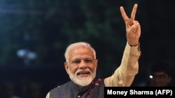 Indian Prime Minister Narendra Modi flashes the victory sign as he celebrates the victory in India's general elections at the party headquarters in New Delhi on May 23.