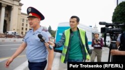 Корреспондент Азаттыка Манас Кайыртайулы пытается получить комментарий у сотрудника полиции на месте протестной акции. Алматы, 10 июня 2019 года.

