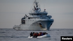 Një gomone e mbushur me emigrantë kalon pranë një anijeje të marinës franceze rrugës drejt Anglisë në Kanalin Anglez, Britani, maj 2024.