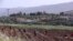 The Israeli village of Metulla, background, is seen from the Lebanese-Israeli border as Syrian farmers work in the village of Kfar Kila, in southeast Lebanon, Wednesday, May 20, 2020. Twenty years after Hezbollah guerrillas pushed Israel's last troops fro