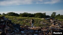 Žena hoda kroz ruševine u naselju Sunshine Hills nakon što je serija tornada pogodila okrug Laurel, u Londonu, Kentucky, SAD, 17. maja 2025.