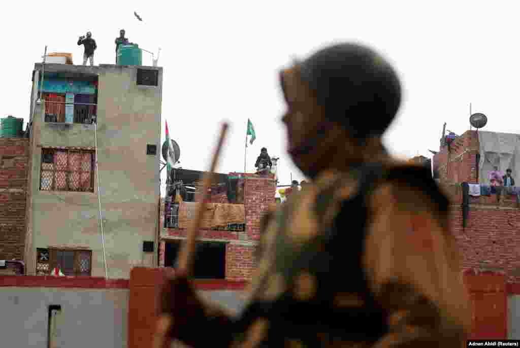 A policeman stands guard as residents watch from their balconies in Seelampur on December 17.