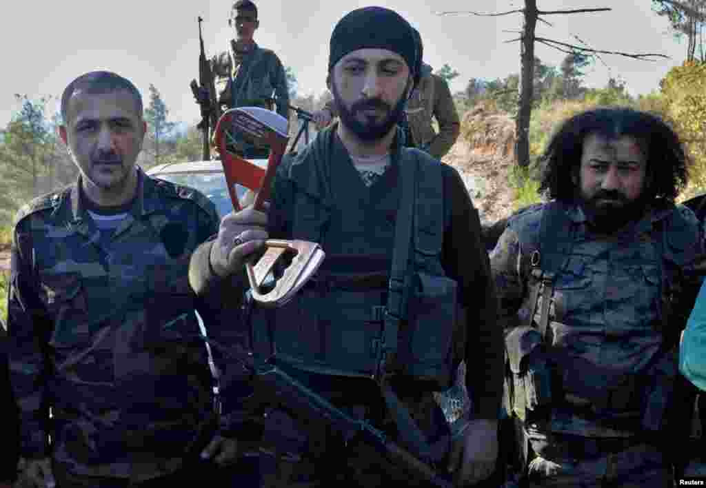 Альпаслан Челик (в центре), заместитель командира бригады сирийских туркмен (туркоманов), держит в руках часть парашюта, принадлежавшего одному из членов экипажа сбитого российского самолета &nbsp;