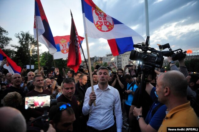 Bosko Obradovic waves a Serbian flag during protests in Belgrade in 2020.