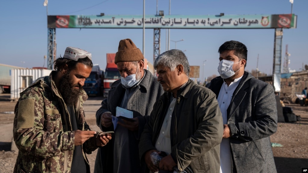 A Taliban fighter checks the passports of Afghans crossing into Iran at the border crossing of Islam Qala in the western Afghan province of Herat.