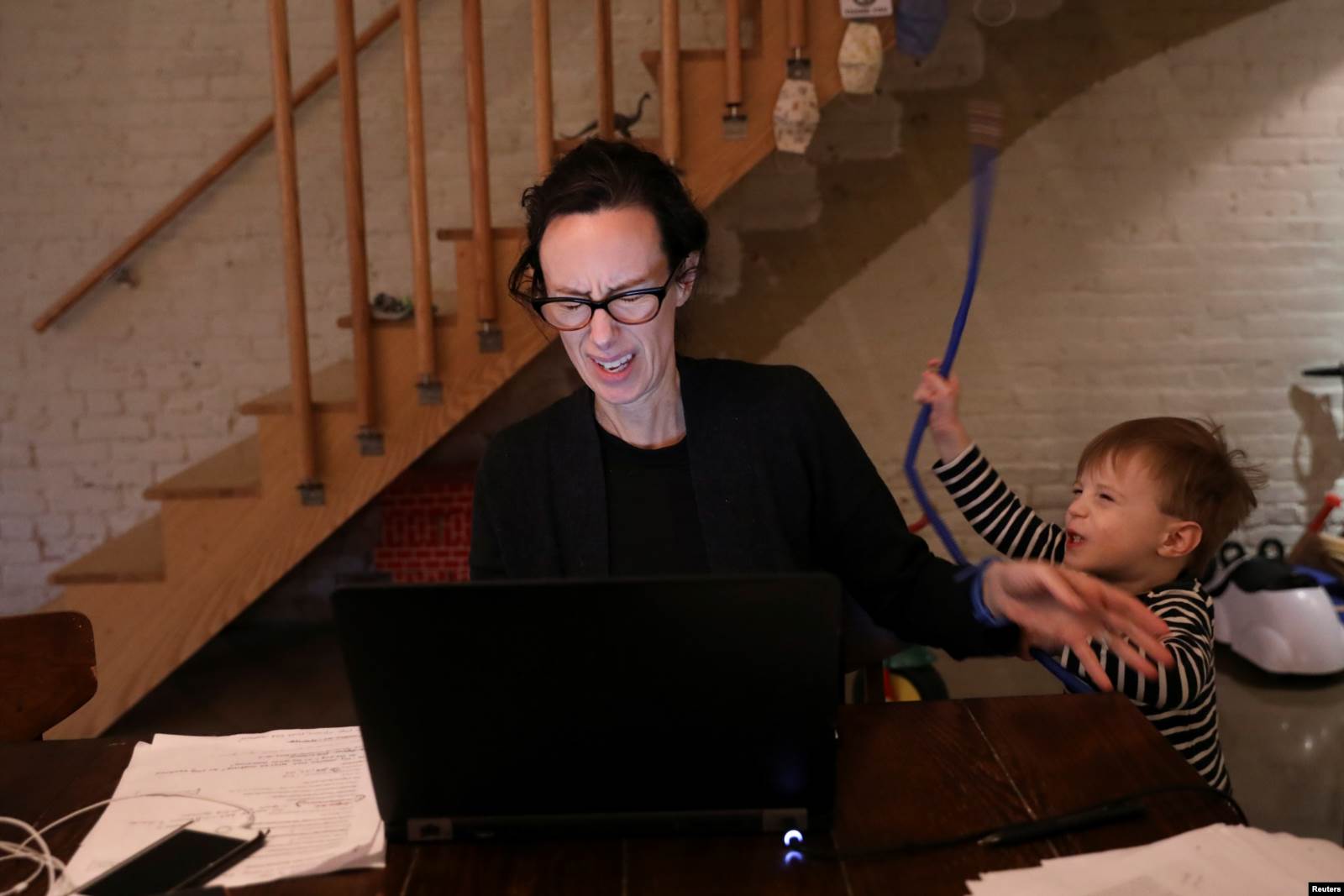 Një djalosh i vogël duke tentuar të aktrojë kinse është zjarrfikës pengon nënën e tij teksa punon nga shtëpia