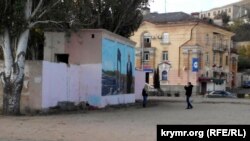 Парень фотографирует девушку на фоне граффити с изображением Владимира Путина на набережной Керчи 