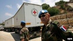 French UN peacekeeping soldiers walk behind Red Cross trucks at the Lebanese-Israeli border in 2008.