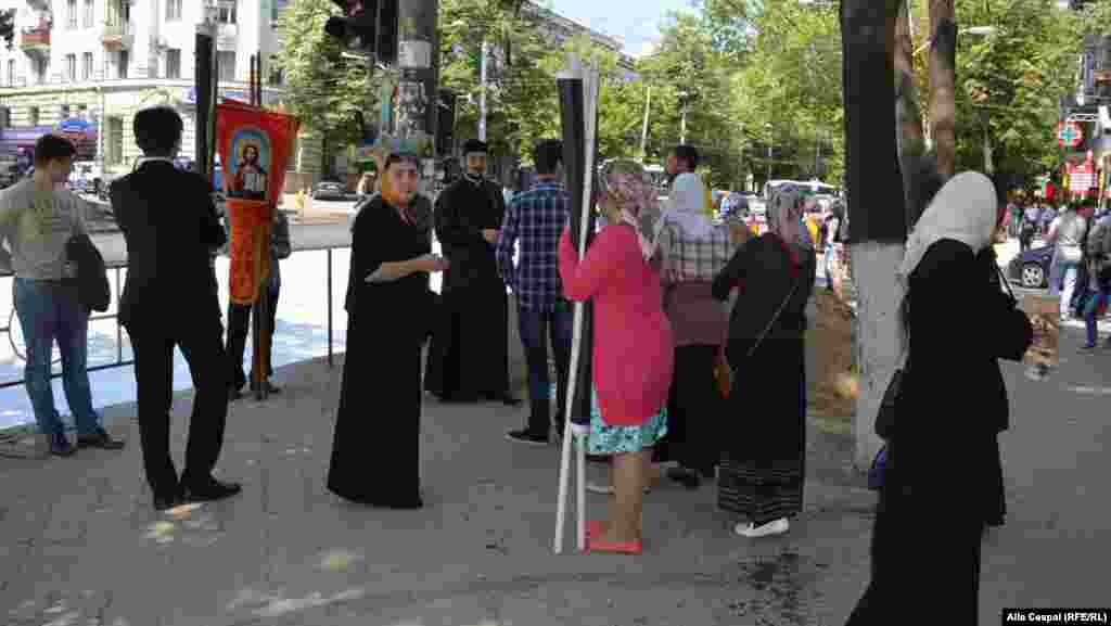 Preotul Valuţă împreuna cu un grup de enoriași stropesc cu aghiasmă în apropierea locului unde se adunat participanții la marșul LGBT.