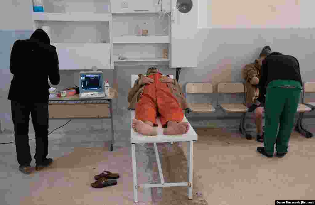 SYRIA -- A foreign prisoner, suspected of being part of the Islamic State, lies on top of an examining table next to a doctor inside a prison in Hasaka, Syria, January 7, 2020.