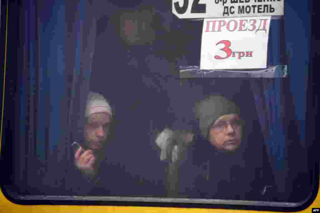 People look from a bus window at the body of a man lying in the street after shells hit a residential area, killing two civilians, in Donetsk&#39;s Kyibishevsky district.