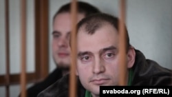 Alyaksandar Atroshankau sits in a barred cage in a Minsk court room.