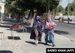 Dy gra afgane të veshura me burka duke kaluar pranë Ministrisë së Mbrojtjes. Kabul, 28 shtator, 1996.