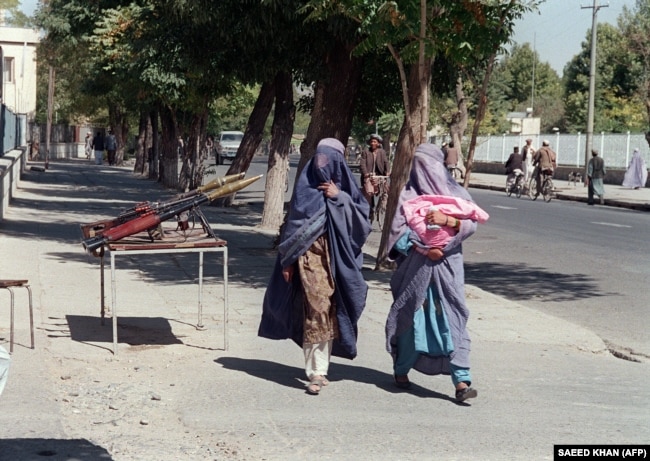 Dy gra afgane të veshura me burka duke kaluar pranë Ministrisë së Mbrojtjes. Kabul, 28 shtator, 1996.