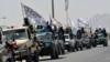 Taliban fighters atop vehicles with Taliban flags parade along a road in Kandahar on September 1 to celebrate after the United States completed its withdrawal from Afghanistan.