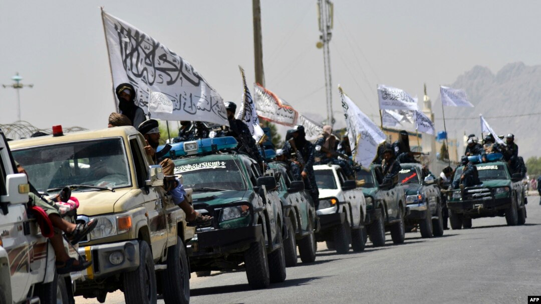 Taliban fighters atop vehicles with Taliban flags parade along a road in Kandahar on September 1 to celebrate after the United States completed its withdrawal from Afghanistan.