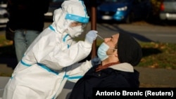 Медицинский работник берет мазок для ПЦР-теста в рамках кампании по проверке на коронавирус жителей Загреба. Хорватия, 23 ноября 2020 года