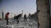 Syrians clear up the rubble of their houses that were destroyed during clashes on the outskirts of Raqqa.