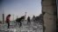 Syrians clear up the rubble of their houses that were destroyed during clashes on the outskirts of Raqqa.