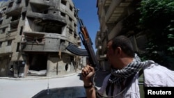 A Shi'ite fighter holds his weapon while patrolling a road at Sayeda Zainab area in Damascus in May 2013.