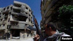 Syria -- A Shi'ite fighter holds his weapon while patrolling a road at Sayeda Zainab area in Damascus, 26May2013