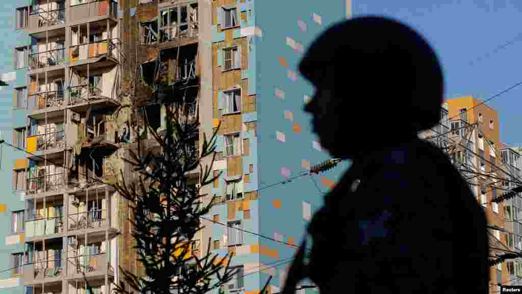 Russian security forces stand guard near the damaged residential area.