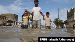 People wade through flood water as they make their way on an inundated street after heavy downpour in Karachi on August 31. 