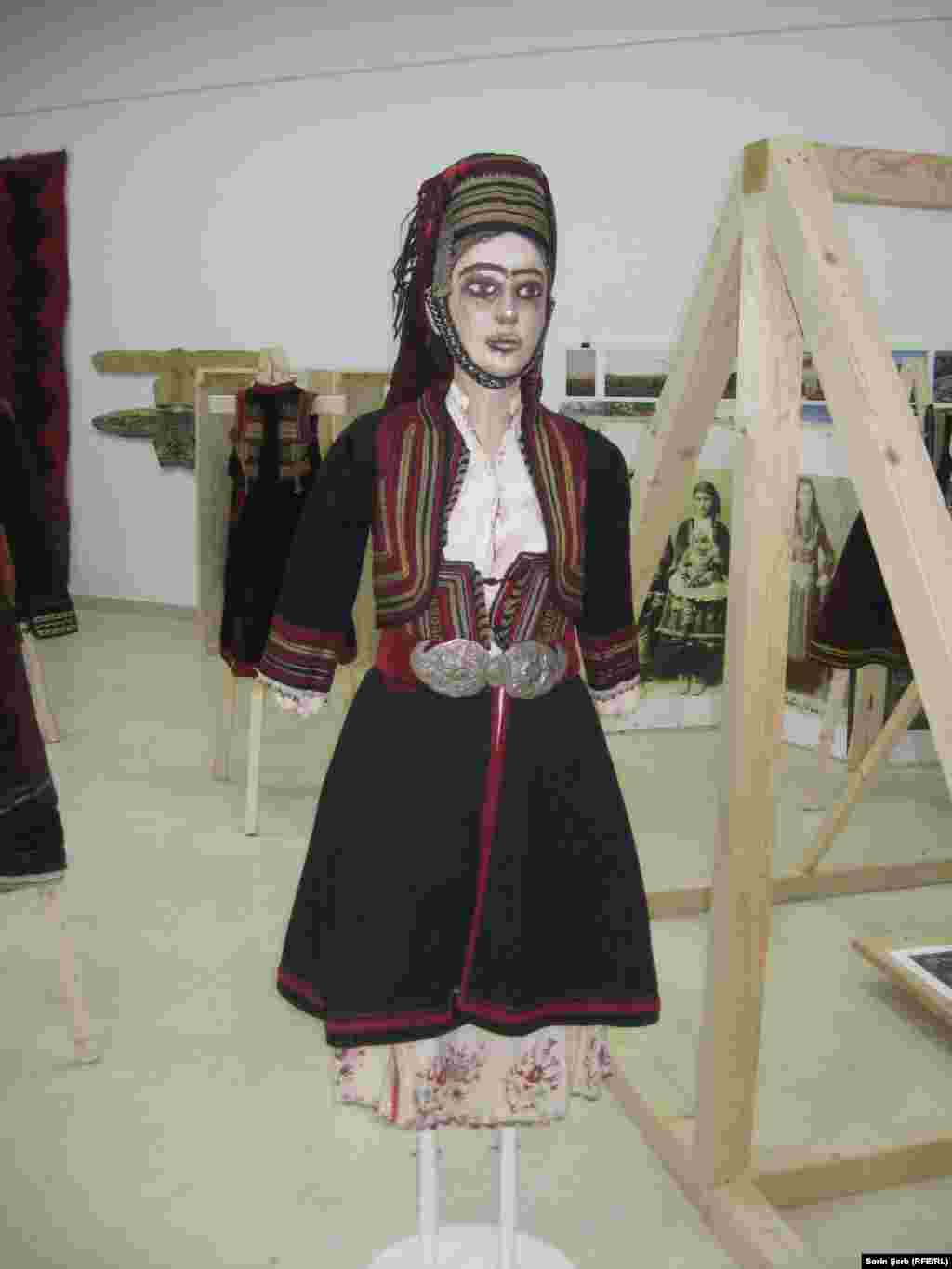 Costum femeiesc grămostenesc se compune din câmeași/ cămașă cu poale, origine Dupnița, Rila, bulgaria, încep. sec. XX, (colecția MȚR), cânduși/ sarafan, Dobrogea, sec. XX (colecția MȚR) mintanŭ/ vestă cu mâneci, Dobrogea, sec. XX, (colecția MȚR), câciulâ di șiacŭ cu mâyuri/ căciulă din aba cu lătițare, Dobrogea, sec. XX, ((colecția MȚR)), minghiuș di câciulâ/ cercel de tâmplă, podoabă pentru căciulă, (colecția Daniel Nancu), lâhurâ cu leasâ/ basma, (colecția&nbsp; Daniel Nancu pafta &bdquo;lacrimi&rdquo;, pe cordon catifea creație contemporară, (colecția Daniel Nancu) &nbsp;