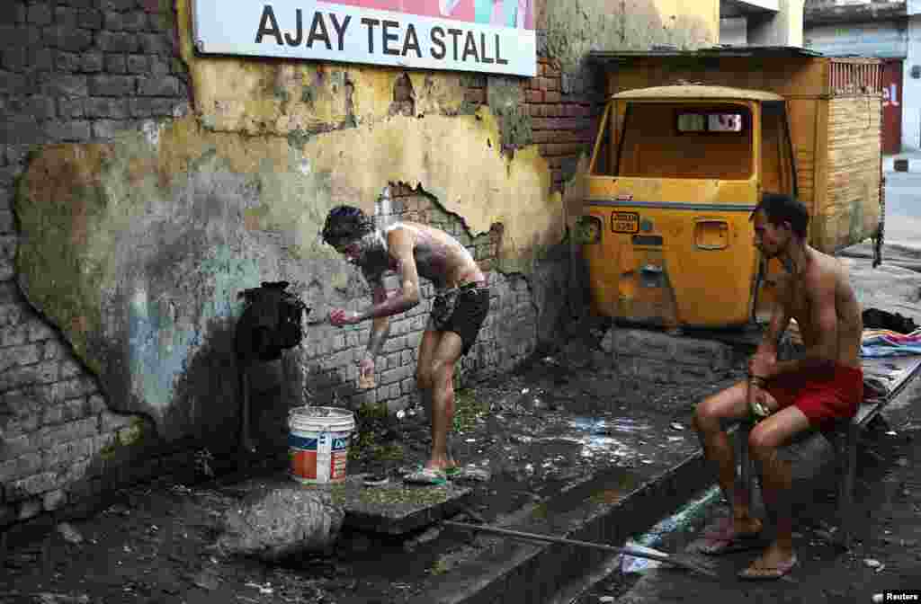 A man bathes at a roadside municipal tap near a market in Indian-administered Kashmir. (Reuters/Mukesh Gupta)