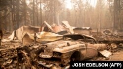 Запален автомобил и куќа за време на пожарот во населбата Индијан Фолс во округот Плумас, Калифорнија. Пожарите кои траеа денови во јули 2021 година изгореа повеќе од 190.000 хектари и беа дел од климатската криза што донесе голема топлина и алармантна суша.