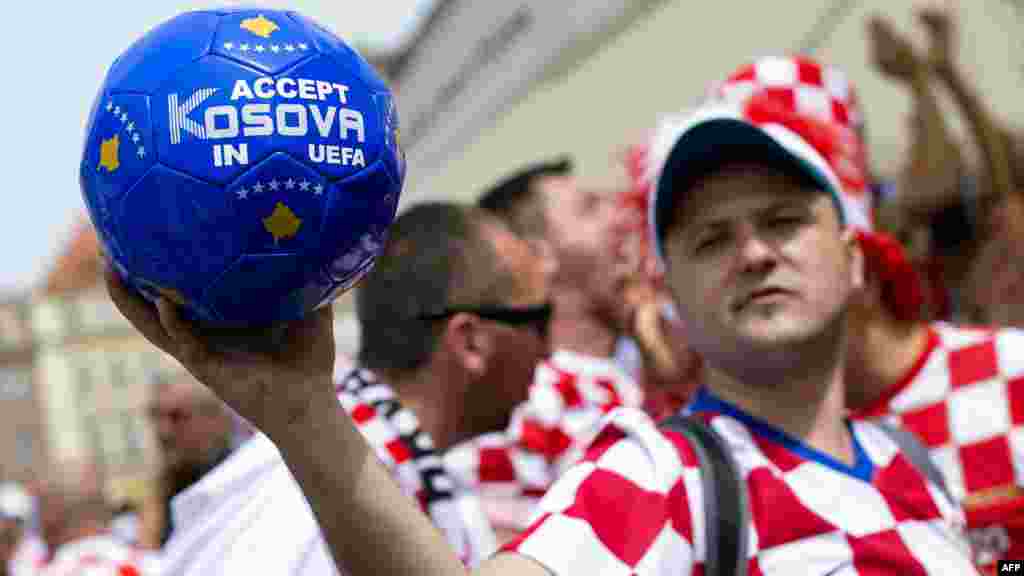 A Croatian supporter holds a ball bearing the sentence &quot;Accept Kosovo in UEFA&quot; in downtown Poznan, Poland. (AFP/Fabrice Coffrini)