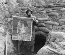 Американски войник с картина на съветския лидер Йосиф Сталин, която е намерена да виси в изоставен севернокорейски бункер през 1950 г.