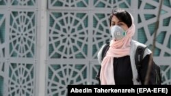 An Iranian woman wearing a face mask walks on a street in Tehran on March 2. 