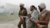 Men carry a person who fainted while queuing up to receive food supplies at a distribution point for North Waziristan's displaced in Bannu.