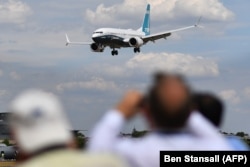 Vizitatorii urmăresc cum un Boeing 737 Max aterizează după o prezentare aeriană în timpul Farnborough Airshow, la sud-vestul Londrei, 16 iulie 2018.