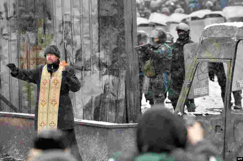 An Orthodox priest tries to stop a clash between protesters and security of Kyiv on January 22. (AFP/Sergei Supinsky)