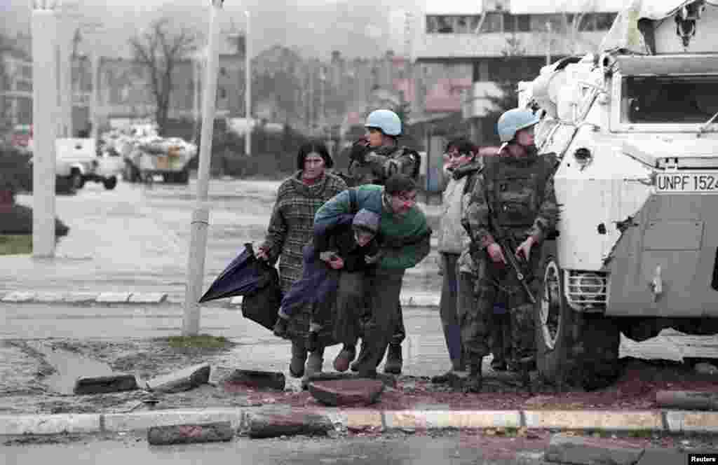 Residents of Sarajevo take cover from sniper fire behind a United Nations Protection Force (UNPROFOR) armored vehicle during the siege of the Bosnia-Herzegovinian capital in 1993.