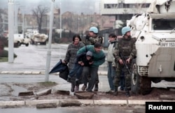 Жителі Сараєва ховаються за БТРом миротворців ООН від снайперського вогню під час облоги міста військами боснійських сербів. Фото 1993 року
